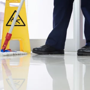 low-angle-closeup-person-cleaning-floor-with-mop-near-yellow-caution-wet-floor-sign